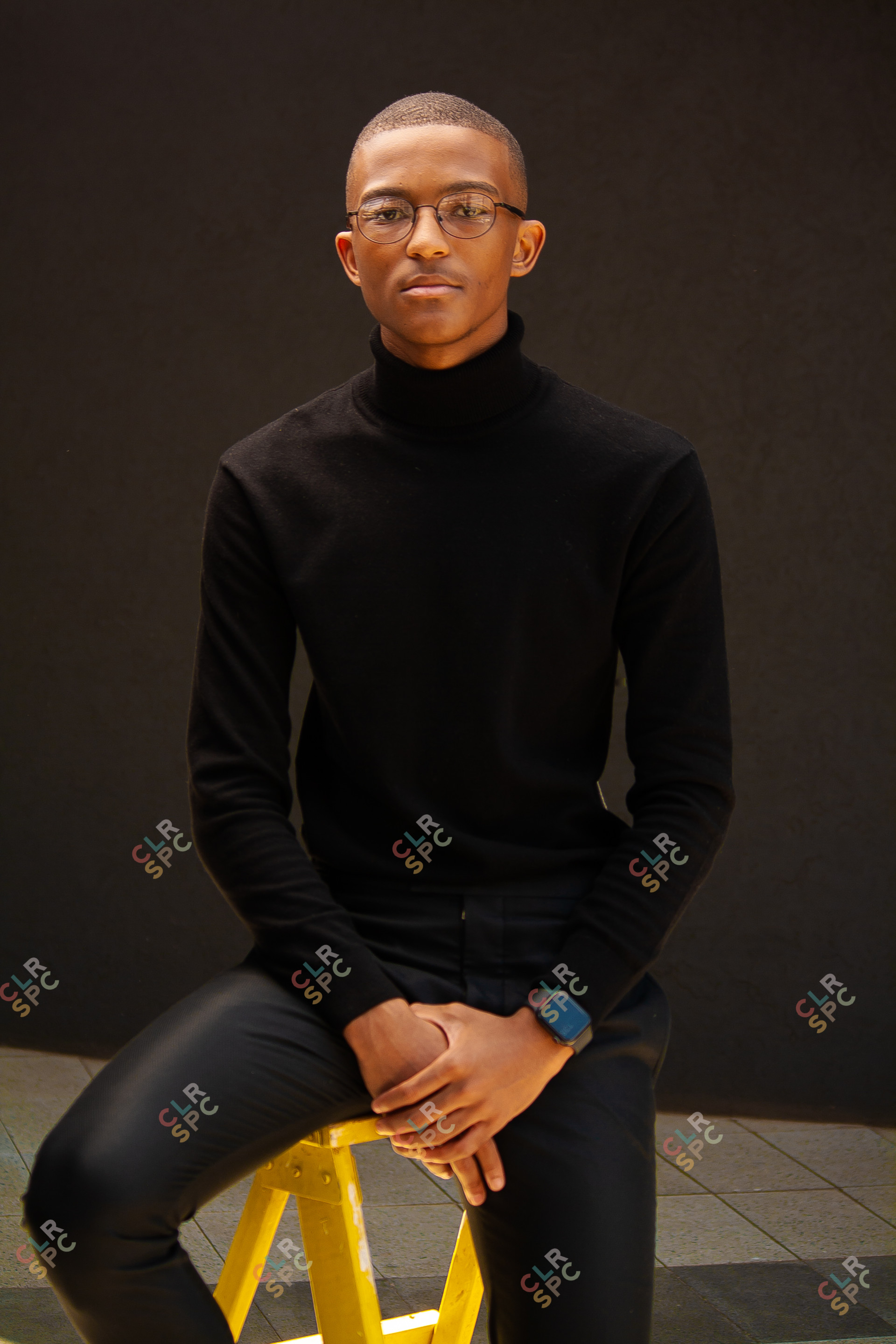 Black man sitting on a yellow ladder