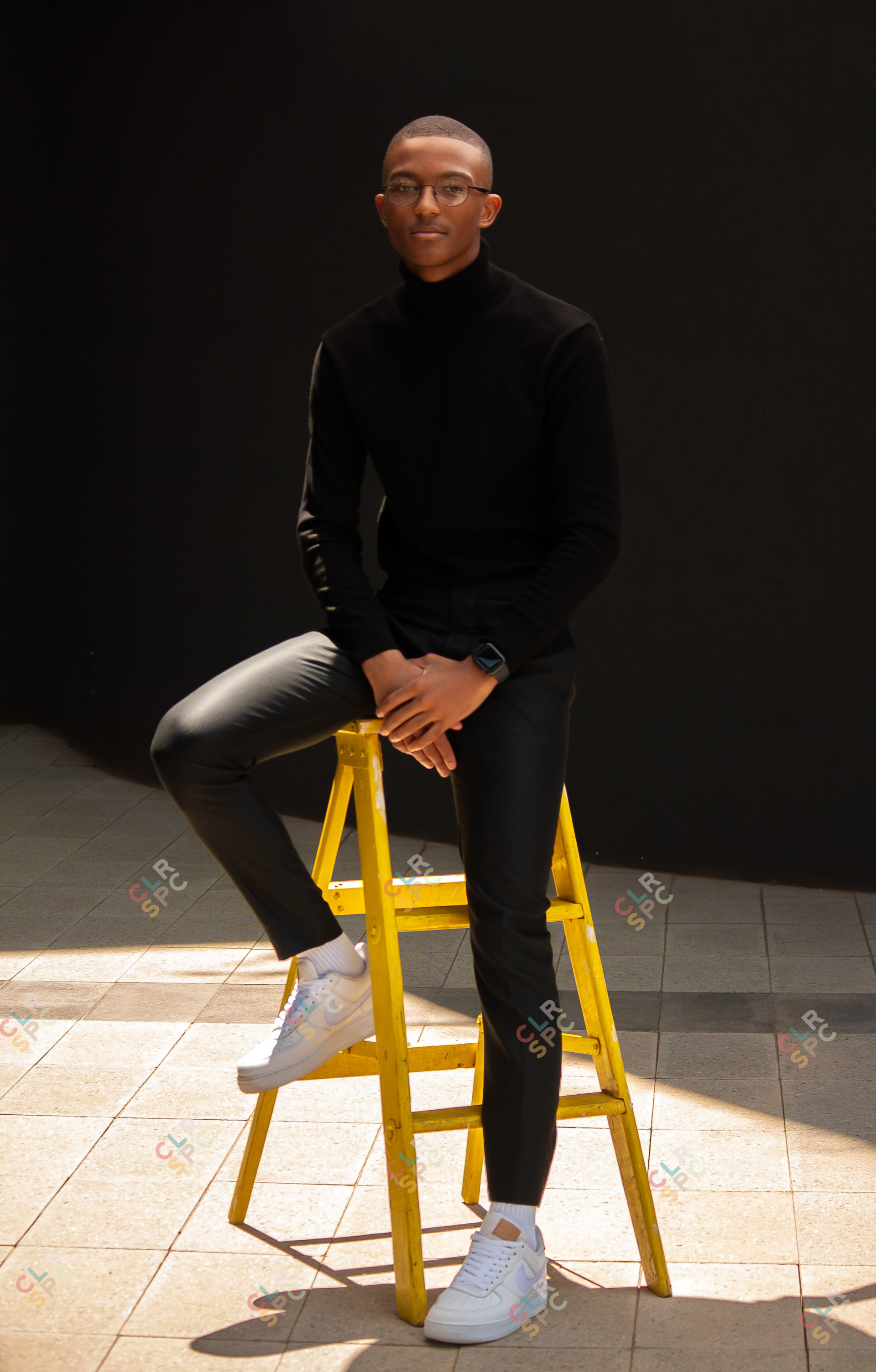 Black man sitting on a yellow ladder