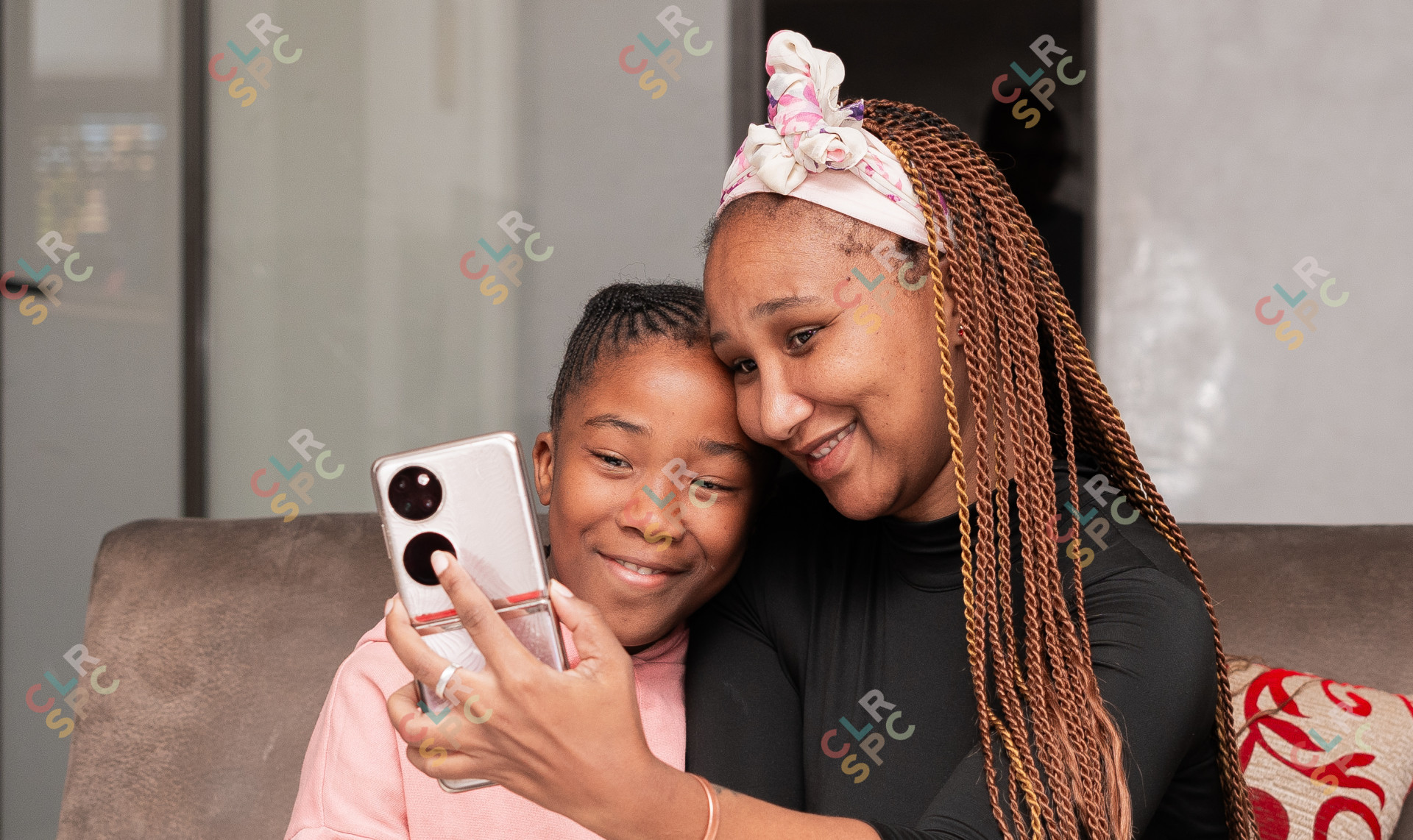 Portrait of black mother and daughter smiling on the couch taking a selfie.