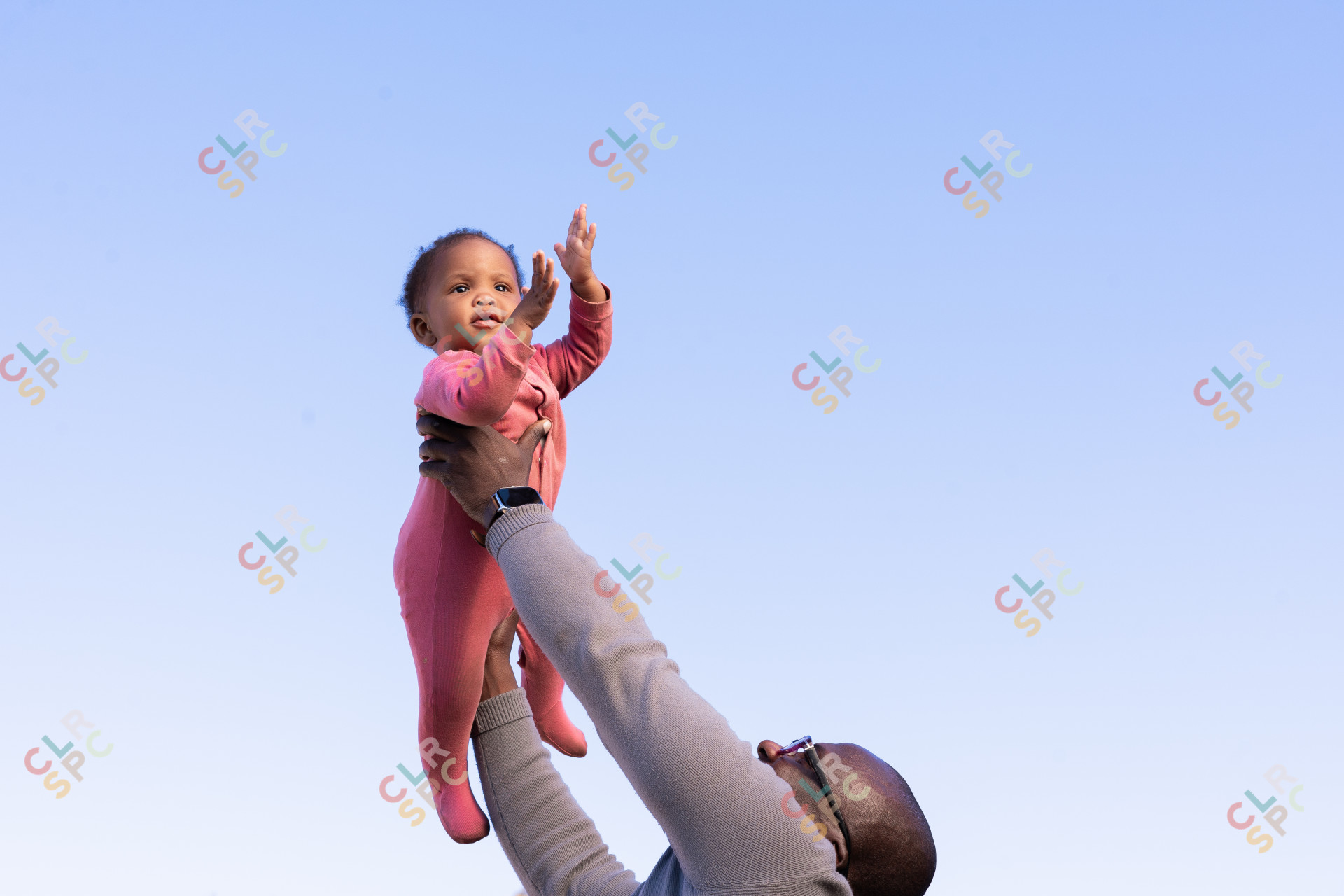 Black father holding daughter in the air with blue sky in the background in South Africa.