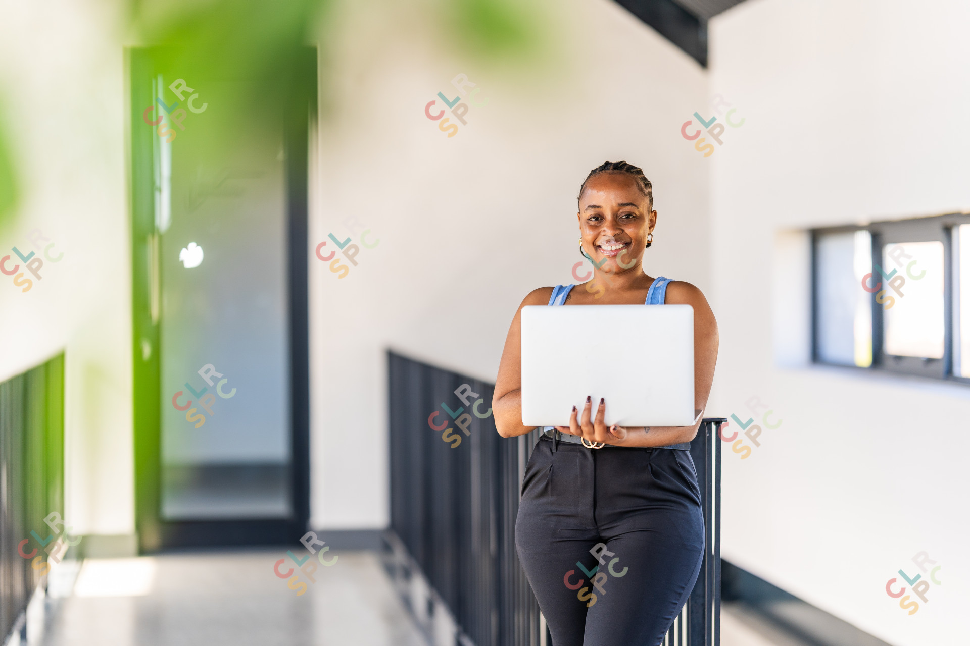 African black business woman holding a laptop at office. Smiling young African businesswoman looking up while working on laptop.