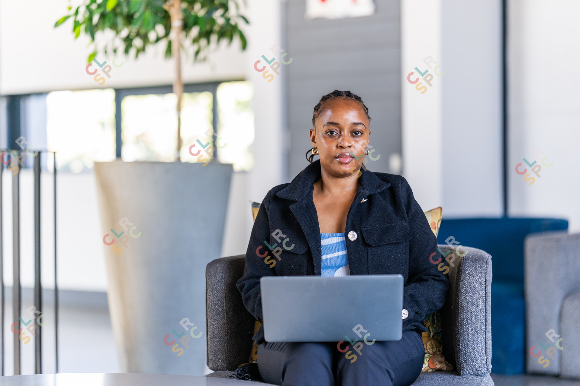 Professional black woman working on laptop at the office wearing a black jacket.