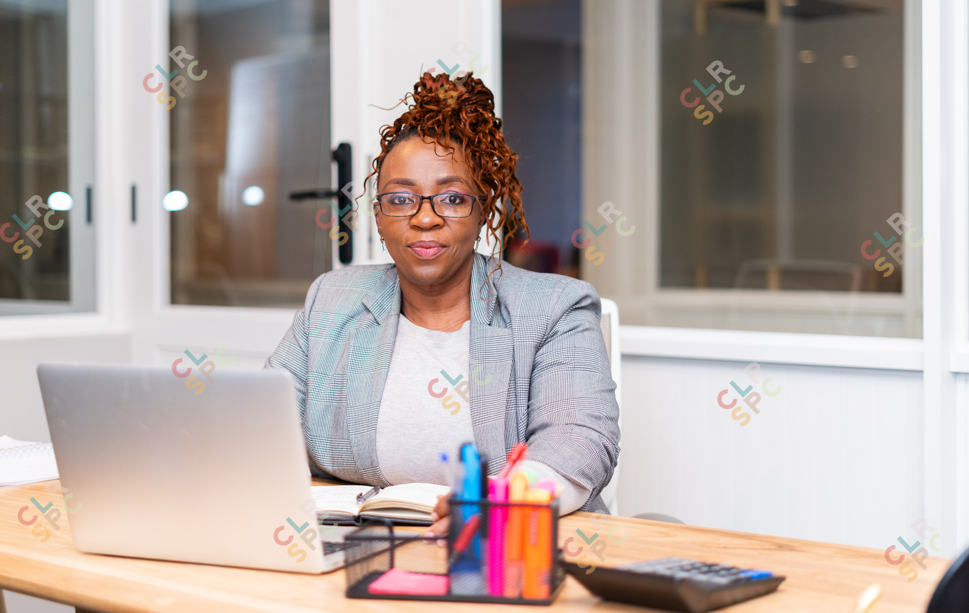 African mature black woman sitting at desk with laptop wearing glasses at the office.