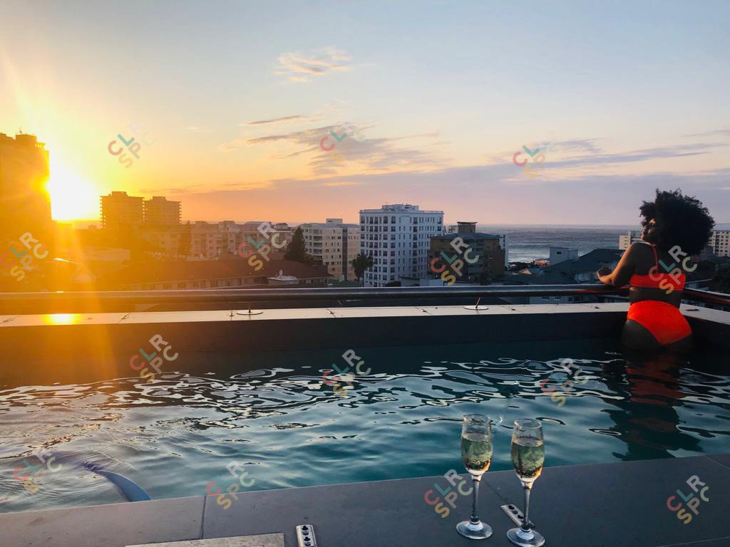 Black woman on a rooftop pool with champagne