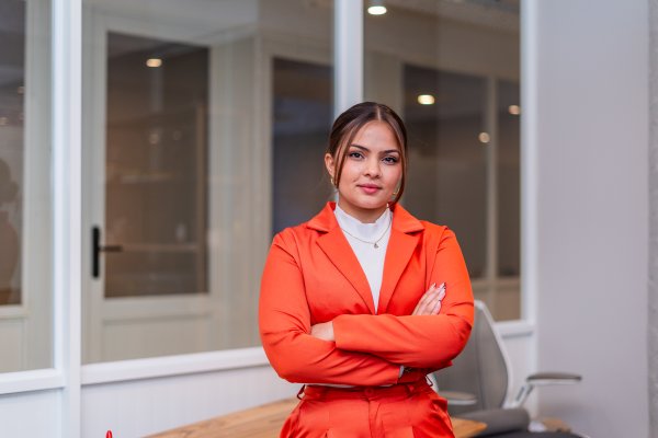Professional South African woman wearing orange suit at the office.