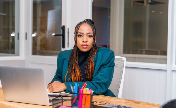 Young vibrant African woman sitting at her desk with a laptop in front of her.